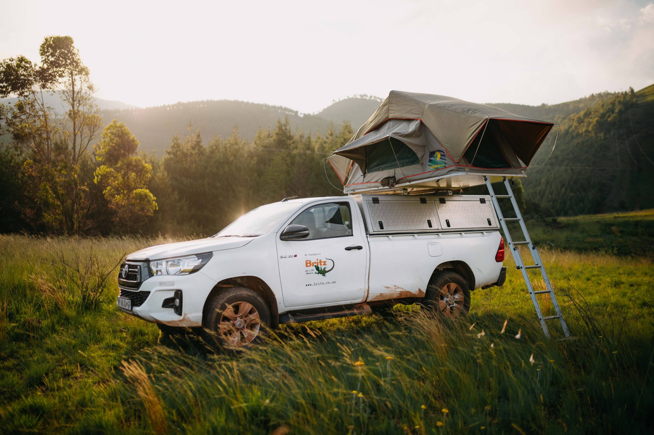 Toyota Hilux Single Cab with rooftop tent open at dusk in the mountains