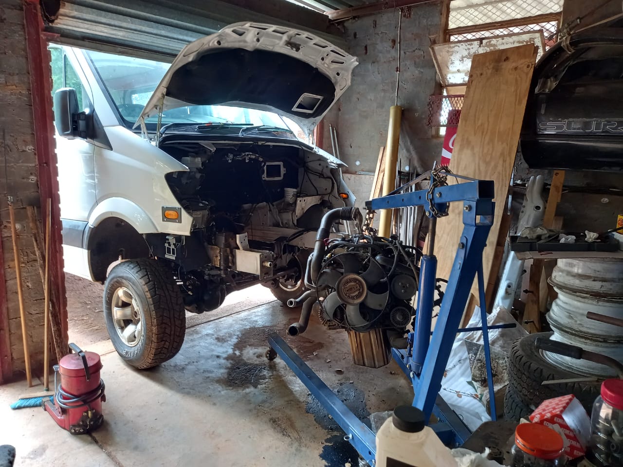Mercedes Sprinter 4x4 conversion mid-build — engine on crane in workshop